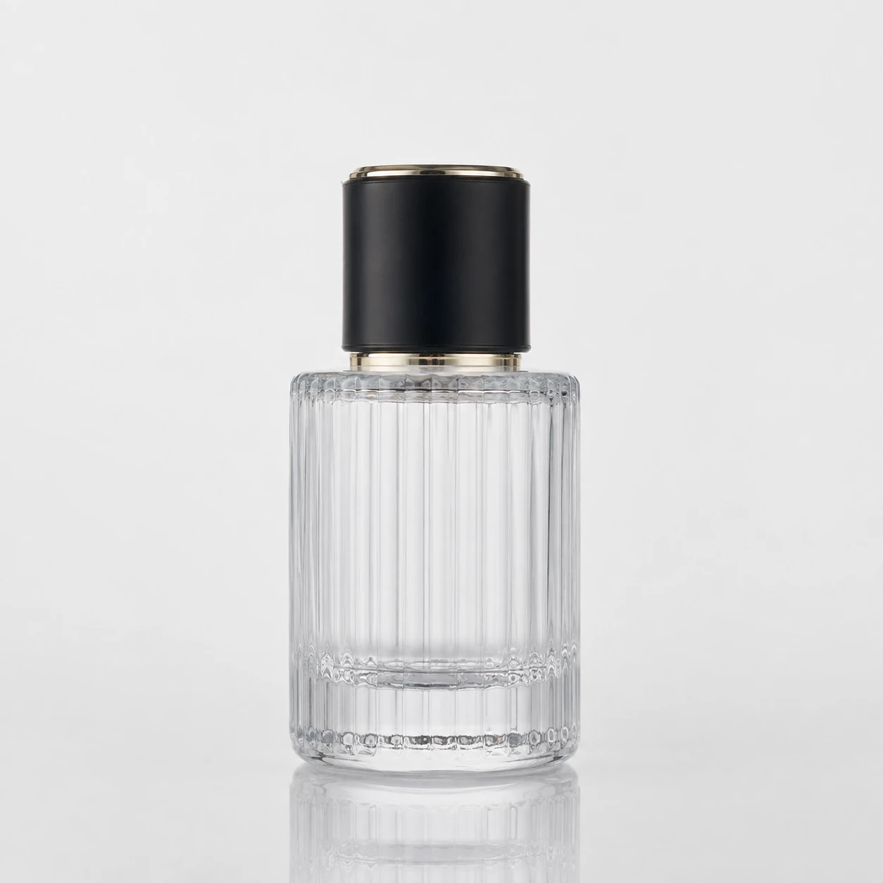 Clear cylindrical glass perfume bottle with vertical ribbed texture and black cap