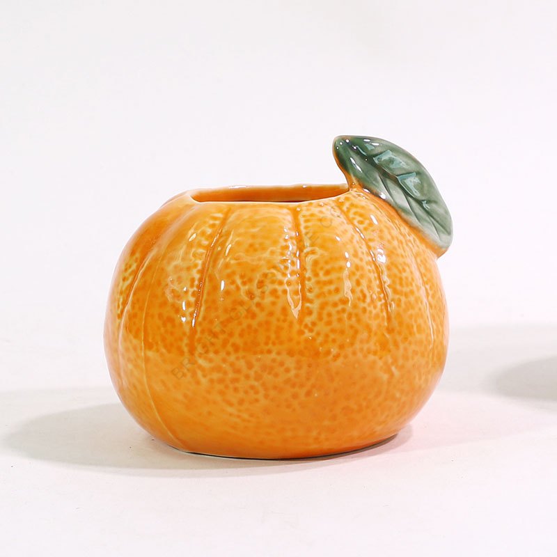 Pumpkin-Shaped Ceramic Candle Jar - group or component view Orange fruit-shaped container with a small green leaf-shaped lid detail.
