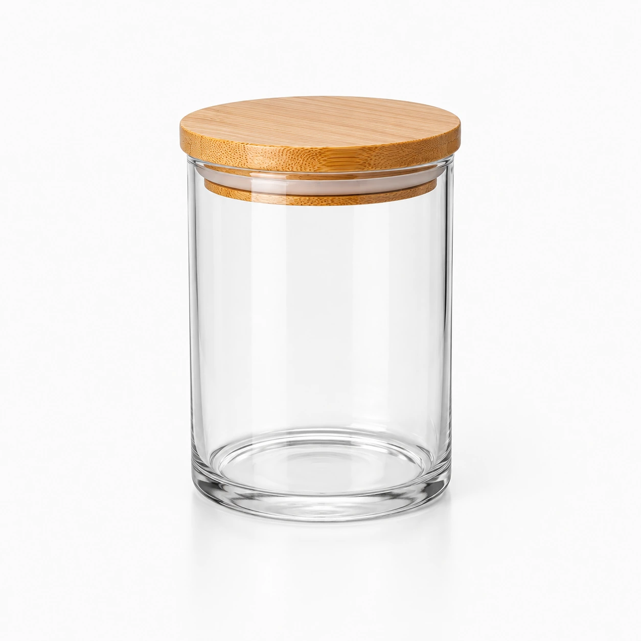 Clear cylindrical glass storage jar with bamboo lid on a clean white studio background.