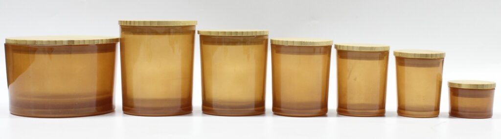 Colored cylindrical containers displayed with small fragrance bottles and accessories.