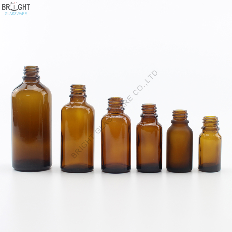 Six amber glass bottles with open screw necks in different sizes