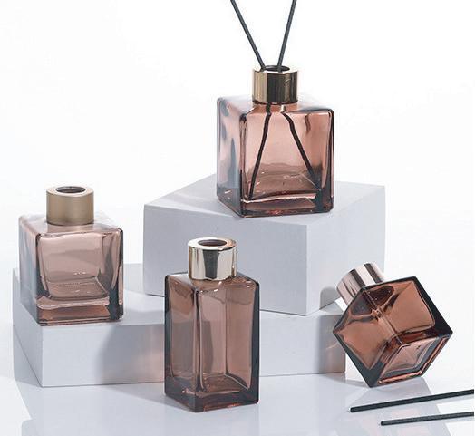 Square tinted diffuser bottles displayed with matching caps and reeds Square tinted diffuser bottles displayed with matching caps and reeds