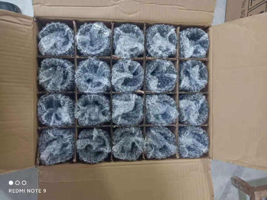 Ceramic candle jars wrapped individually in bubble film and separated in carton cells Open shipping carton filled with individually wrapped containers in a grid.