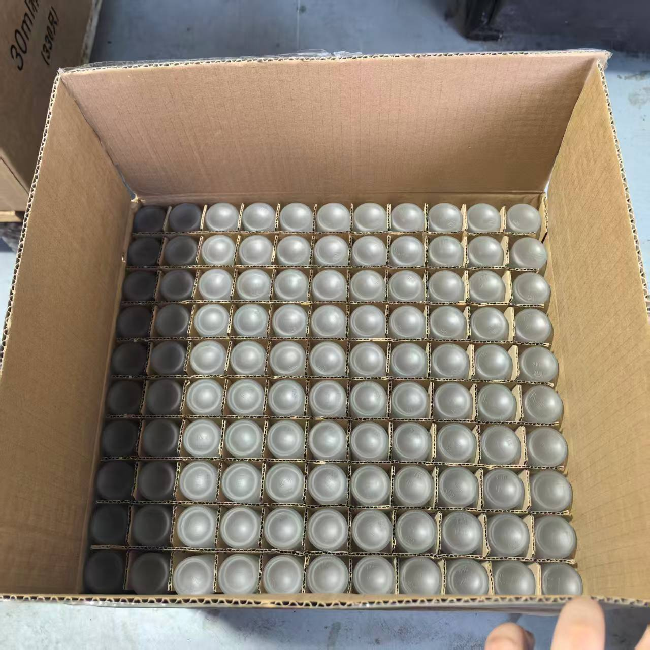 Inverted glass bottles separated by cardboard dividers inside an open carton