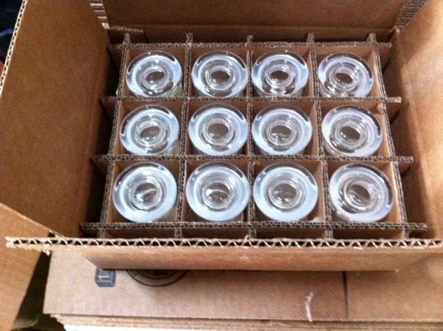 Open carton with clear items arranged in separate round protective compartments.