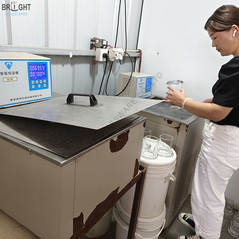 Worker holding a glass container beside temperature-controlled water baths