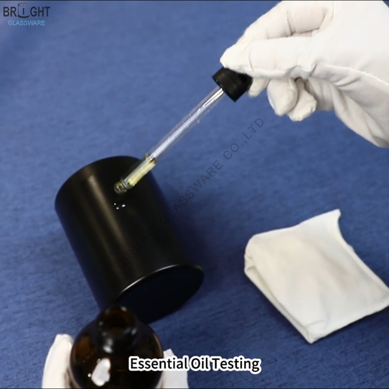 Gloved hand holding a dropper above a black-coated glass container