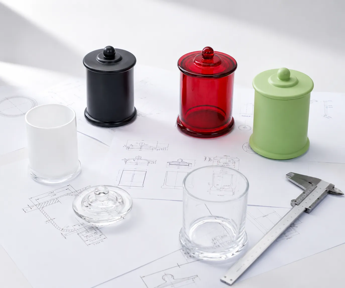 Drawing review to prototype scene with glass bottle and jar samples beside technical design sketches