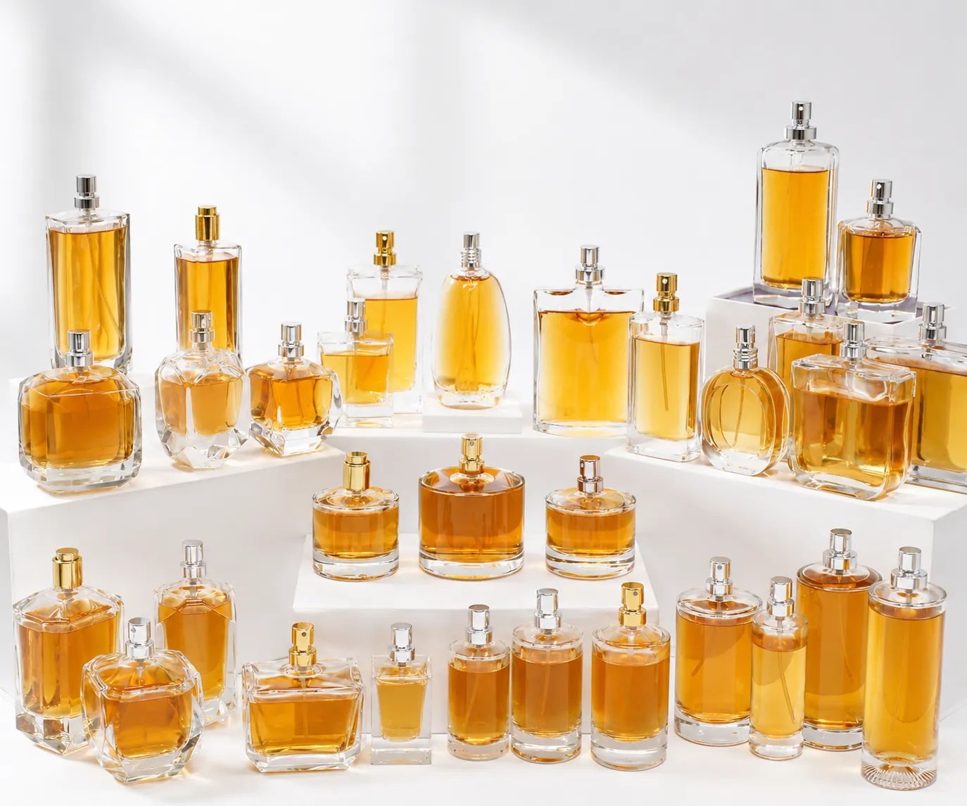 Collection of clear glass perfume bottles with amber liquid in multiple shapes and sizes for fragrance packaging development