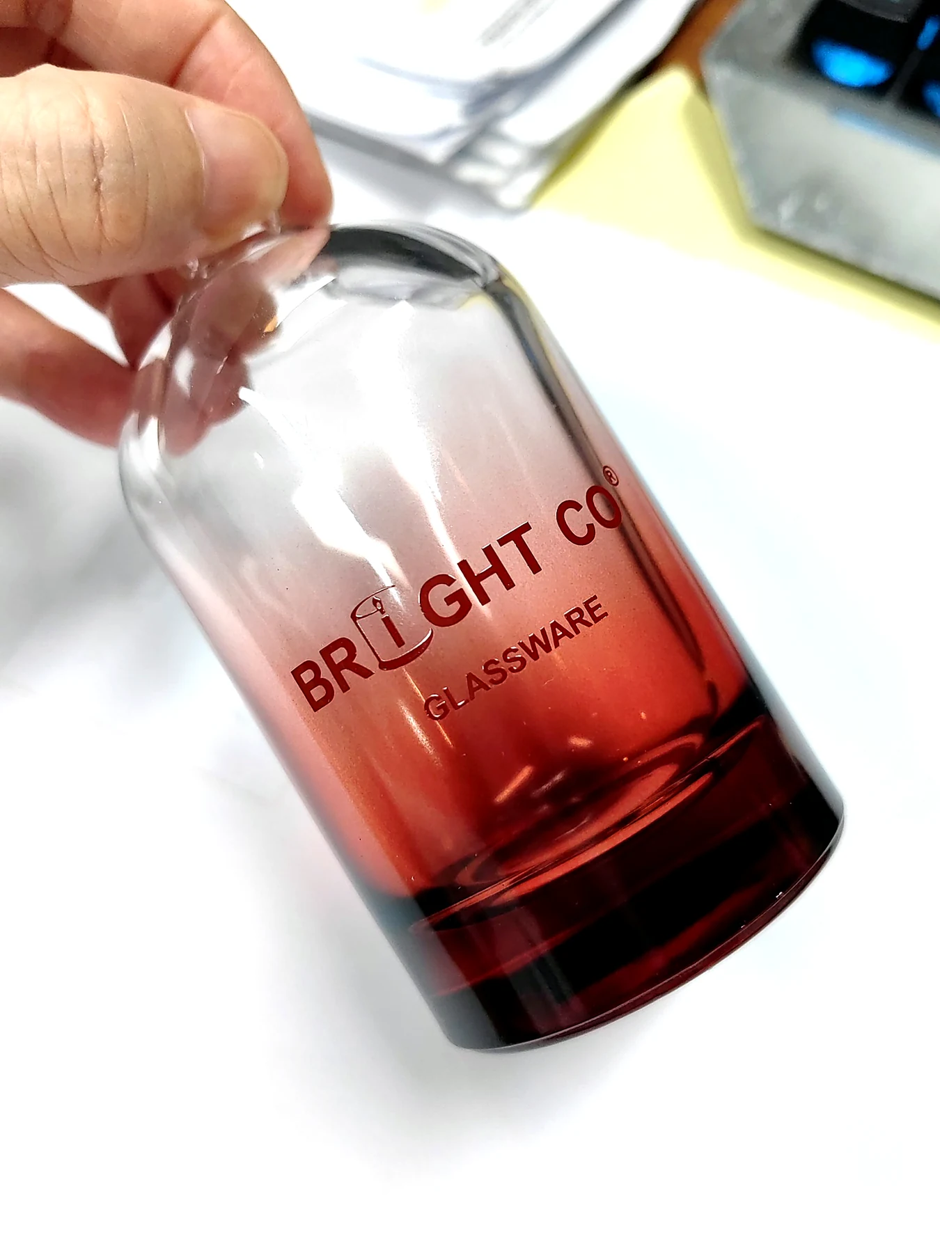 Bright Glassware logo screen-printed on a red gradient glass bottle as a custom branding sample